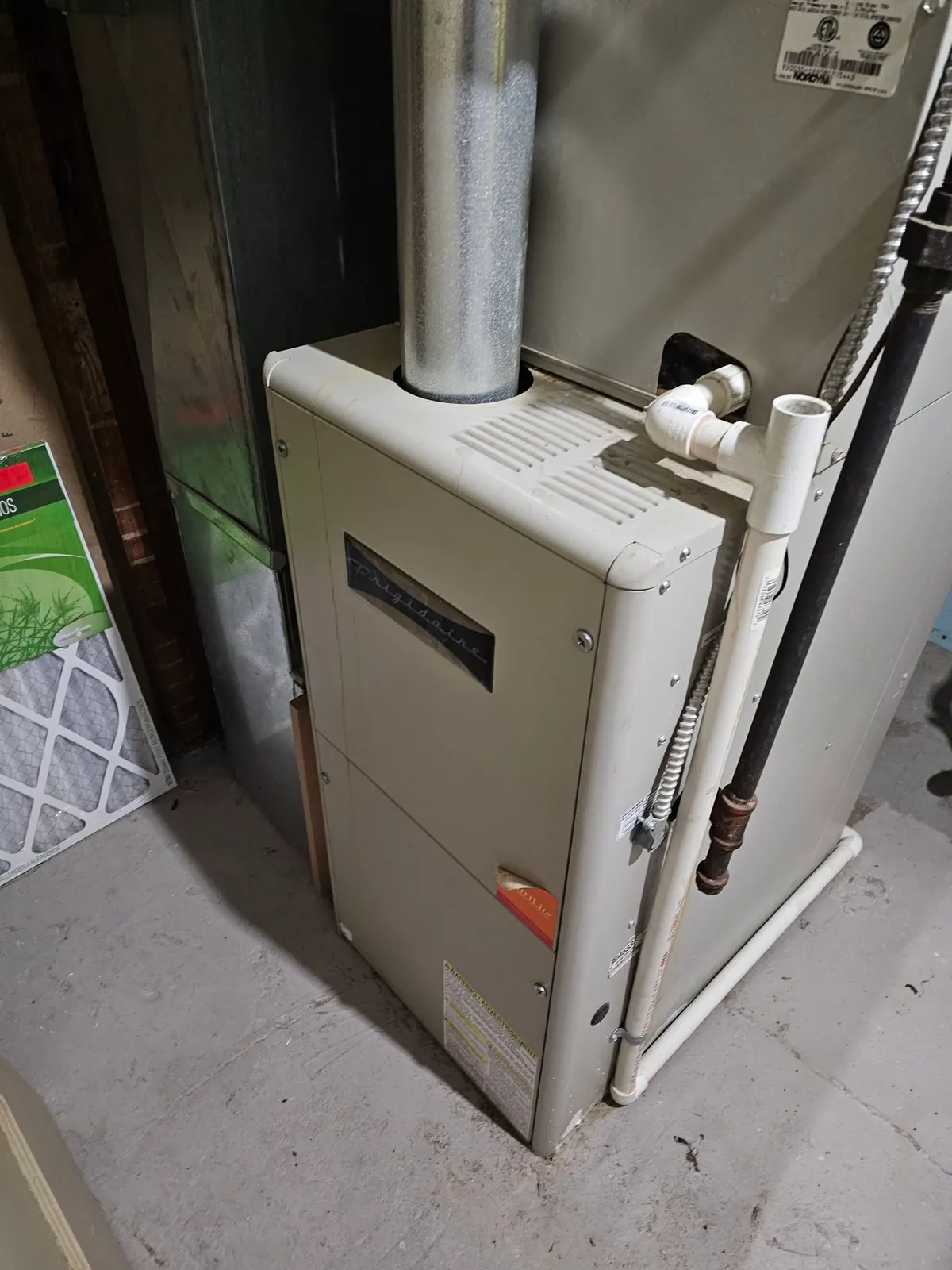 Aging gas furnace in a basement corner with spare filters beside it, the kind of older setup we check on furnace repair calls in Englewood, CO