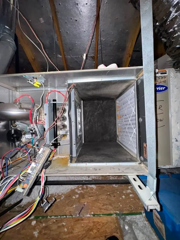 Attic furnace with the blower assembly out and the control board hanging free, partway through a furnace repair.