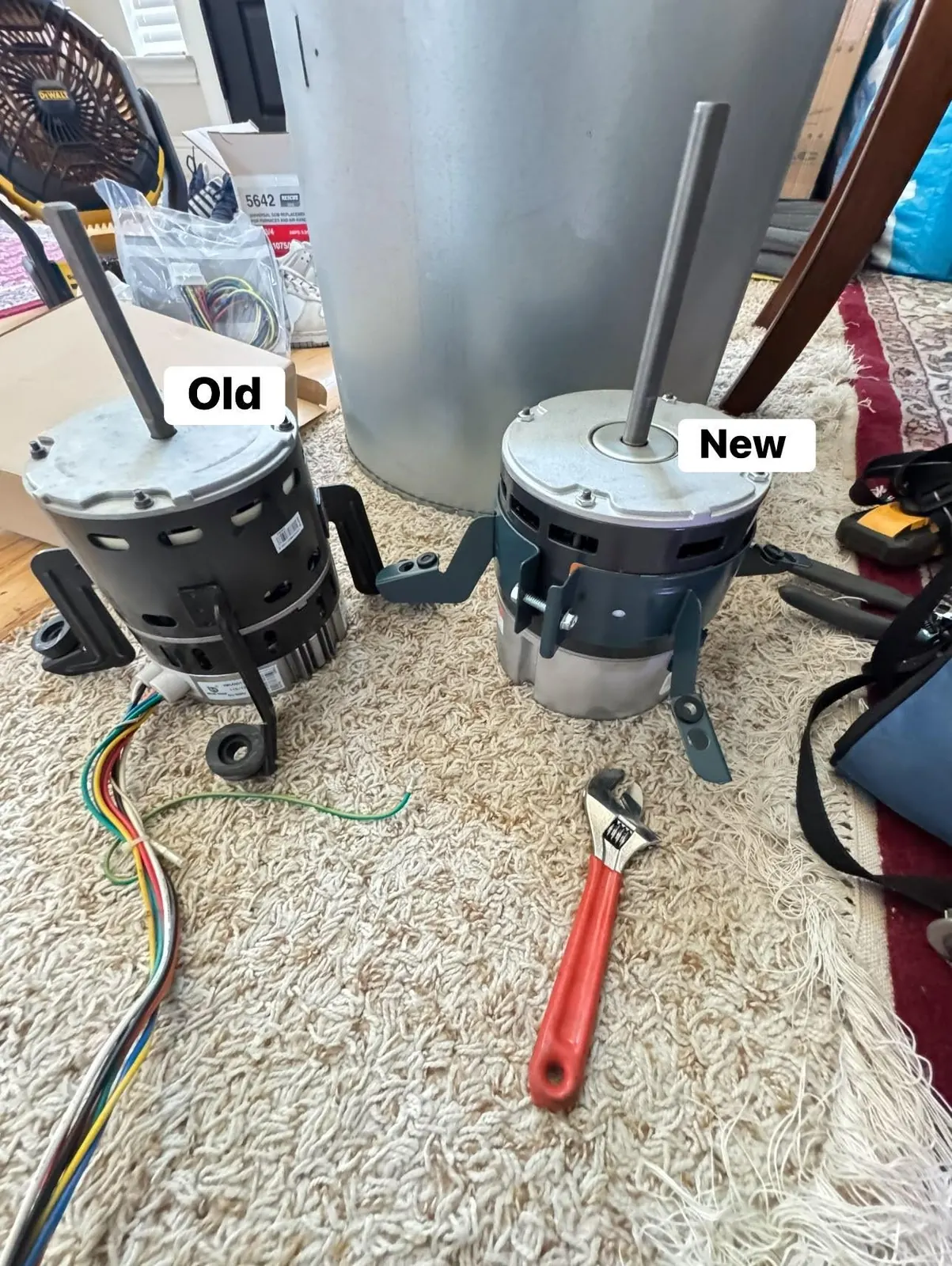 Worn and new furnace blower motors side by side with a wrench, the usual fix for a squealing blower in furnace repair.