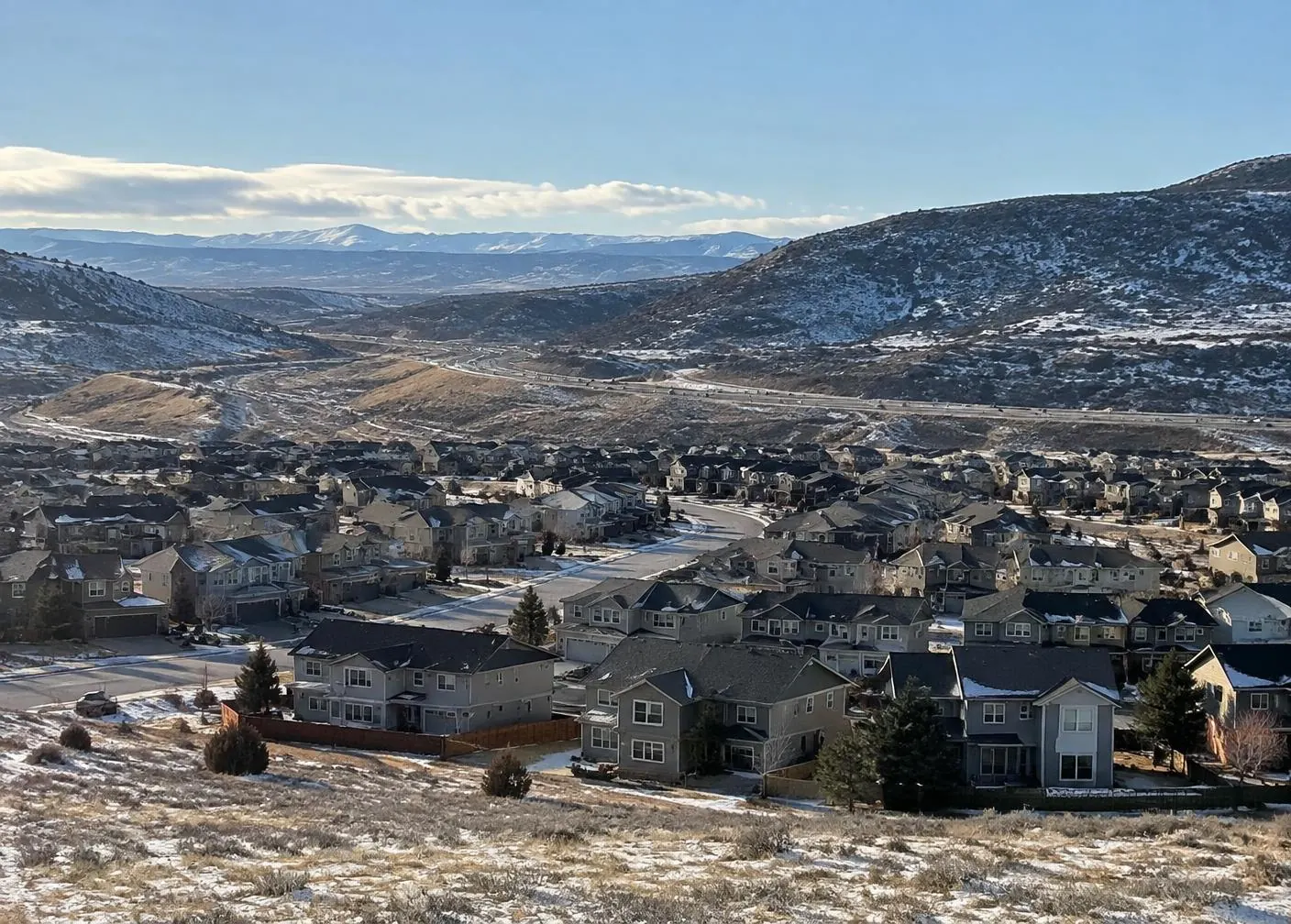 Two-story homes in light snow, foothills and a highway beyond, homes we serve for furnace repair in Highlands Ranch, CO