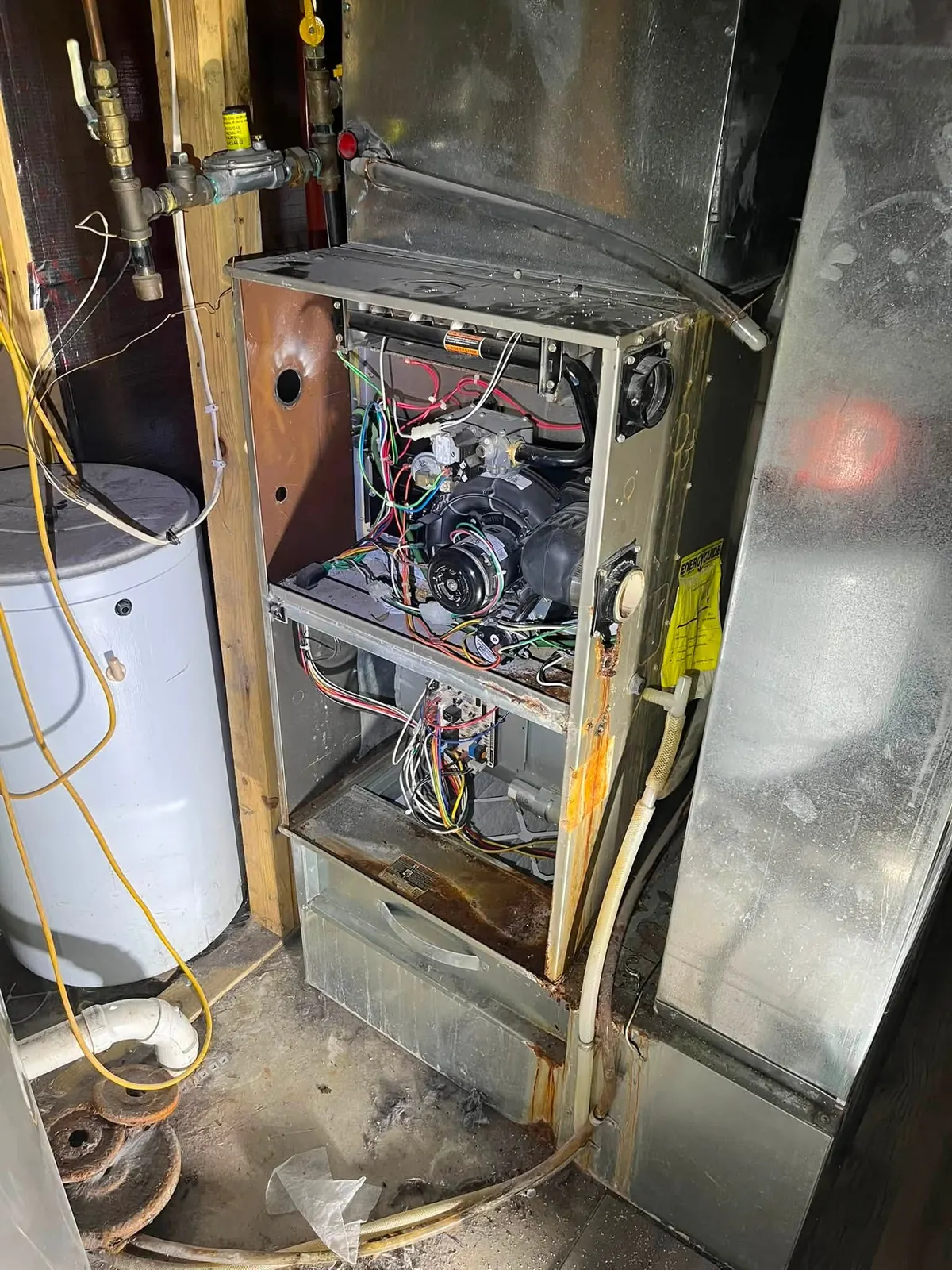 Older gas furnace with the front panels off, showing the draft inducer, gas valve and control board during furnace repair.